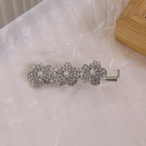 Détail de trois barrettes à fleurs argentées connectées avec des strass étincelants
