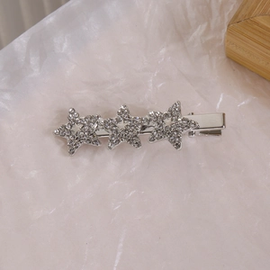 Détail d'une pince à cheveux argentée avec trois étoiles en strass étincelantes