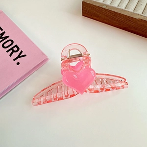 Detailed view of pink heart hair claw clip with glossy acrylic finish and metal spring