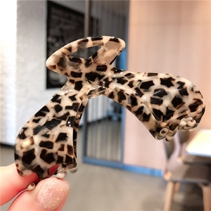 Detail showing high-gloss acetate hair claw clip with tortoise leopard pattern texture