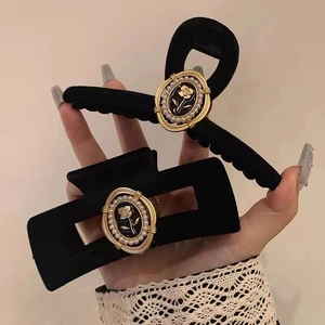 Detail of black velvet hair claws with gold relief rose patterns and faux pearls