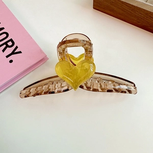 Detail of a large brown hair claw clip featuring a 3D yellow heart and translucent finish