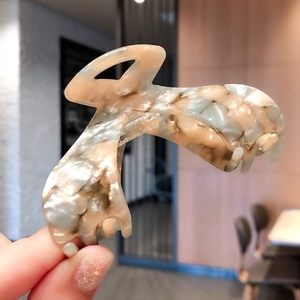 Detail of elegant marble pattern acetate hair claw clip with cream and blue tones