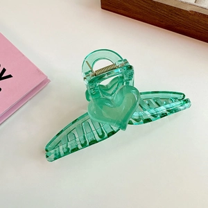 Detailed view of large mint green heart hair claw clip with golden metal spring