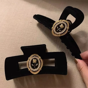 Detail of vintage black velvet hair claw clips with gold rose and pearl emblem