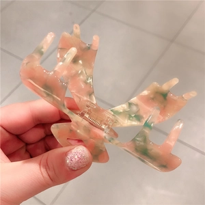 Macro detail of large butterfly acetate hair claw clip with pink and green marble texture