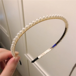 Détails des perles blanches sur serre-tête doré avec embouts de protection noirs