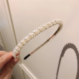 Détail d'un serre-tête tressé à la main avec des perles blanches brillantes de tailles variées