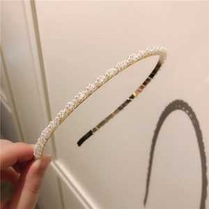 Gros plan sur un serre-tête élégant en perles blanches avec monture en métal fin