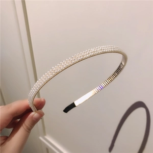 Détail d'un serre-tête à trois rangées de perles avec monture dorée et embouts noirs