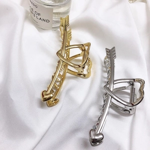 Detail view of gold and silver Cupid arrow heart metal hair claws on white fabric