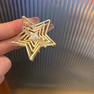 Détail d'une pince à cheveux étoile dorée multicouche ornée de petits strass bleu clair