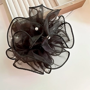 Détail d'un chouchou en organza noir avec perles blanches sur plateau en bois