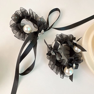 Elegant black organza scrunchies with pearls and ribbon bow detailing on a white table