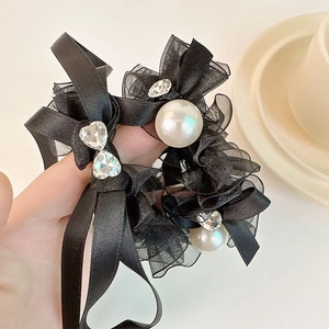 Detailed shot of black mesh bow hair tie with elegant white pearls and rhinestone heart