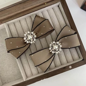 Detailed shot of brown satin bow hair clips with pearls and rhinestones in a wooden box