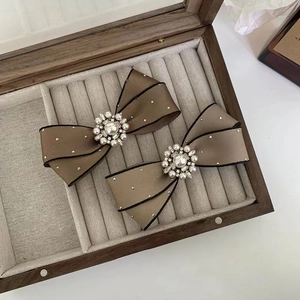 Close-up of pearl and rhinestone bow hair clips on a velvet jewelry organizer box