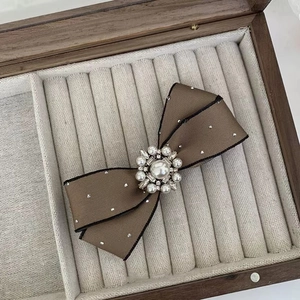 Detailed macro view of the pearl and crystal centerpiece on a brown bow hair clip