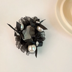 Detail of black organza scrunchie with satin bows, faux pearls and sparkling rhinestones