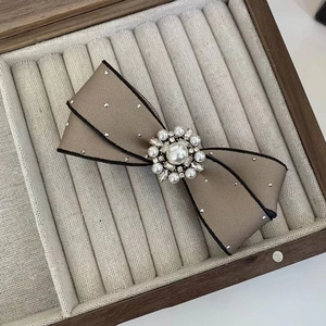 Detailed macro view of khaki bow hair clip with luxury pearl flower and crystals