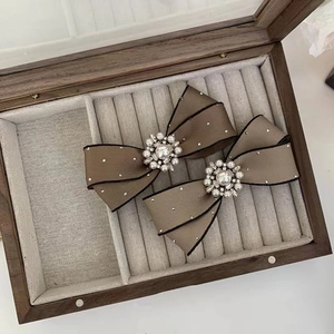 Detail of brown satin bow hair clips with pearls and rhinestones on a jewelry box