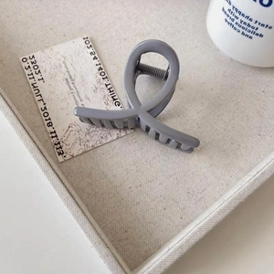 Pince à cheveux torsadée grise mate minimaliste présentée dans un décor esthétique doux