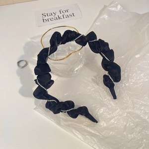 Détail d'un serre-tête plissé en satin noir orné d'une chaîne délicate en strass brillant
