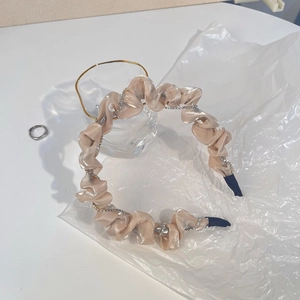 Gros plan sur un bandeau élégant en satin champagne avec chaîne en strass brillant