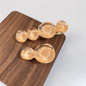 Détail de barrettes en résine ambrée sur socle doré présentées sur un support en bois de noyer