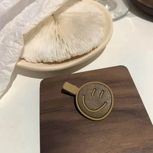 Detailed macro view of khaki leather smiley face hair clip on natural wood block