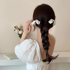 Elegant white ribbon bow hair clips with black edging on braided hair, set of two