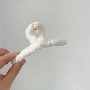 Gros plan sur la pince à cheveux en peluche blanche montrant la texture et le ressort