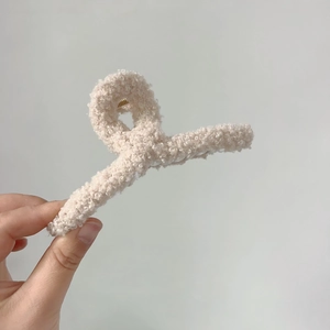 Détail de la grande pince à cheveux en peluche bouclée crème avec ressort en métal doré