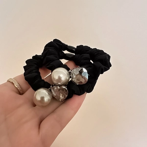 Elegante set di elastici neri con perle bianche e ciondoli di cristallo sul palmo