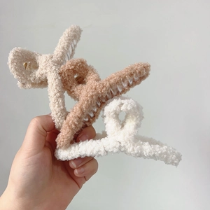 Gros plan de trois pinces à cheveux en polaire pelucheuse blanc, crème et beige