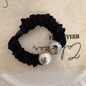 Elegante elastico nero con perla bianca e perla sfaccettata su sfondo artistico