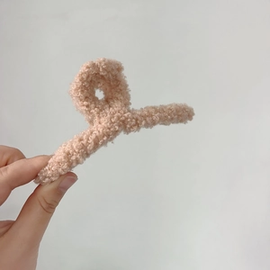 Détail de la texture pelucheuse rose pêche sur la grande pince à cheveux en fourrure