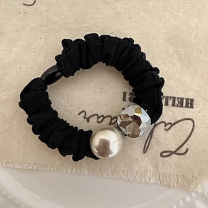 Primo piano dell'elastico nero con elegante perla finta e dettaglio di perla in cristallo