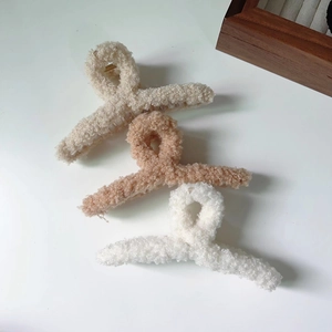 Détail des pinces à cheveux en peluche beige et blanche avec ressorts en métal doré