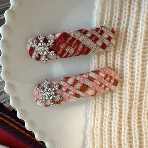 Macro detail of red and pink plaid knit hair clips with sparkling silver snowflakes