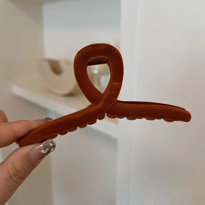 Detail of large caramel red velvet hair claw clip with cross design and soft texture
