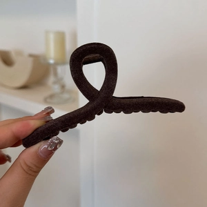 Detail of cross-knotted dark brown velvet hair clip with elegant matte texture