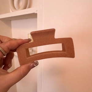 Close-up of matte brick red rectangular hair claw clip with velvet texture