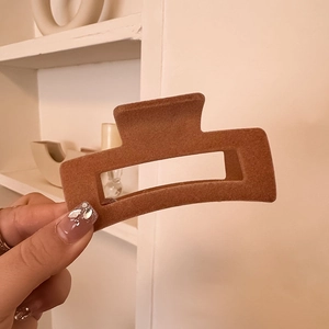 Detail view of brown velvet rectangular hair claw clip held by hand for a daily hairstyle