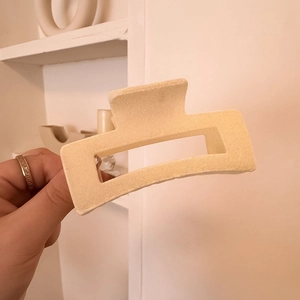 Detail of a large matte cream rectangular claw clip showing its hollow geometric structure