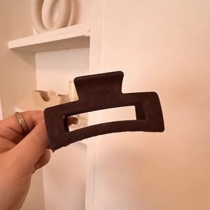 Detail shot of a large rectangular dark brown velvet hair claw clip held by hand