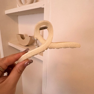 Detail of a large cream matte hair claw clip featuring a stylish twisted ring design