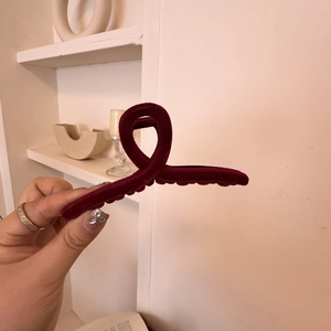 Close-up of a burgundy velvet hair claw clip with a vintage French cross design