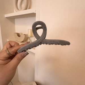 Close-up of a large dark grey velvet hair claw clip with a minimalist twisted cross design