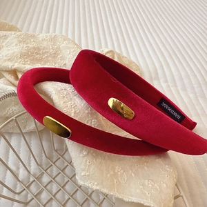 Detail view of red velvet headband with gold logo and handmade label on white lace